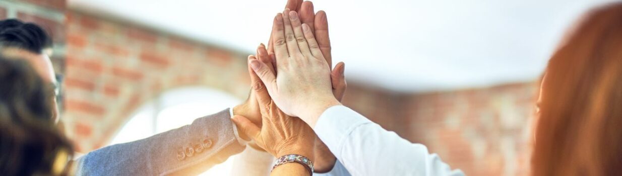 Fünf Personen geben sich ein High-Five - Symbolbild für das Unternehmen