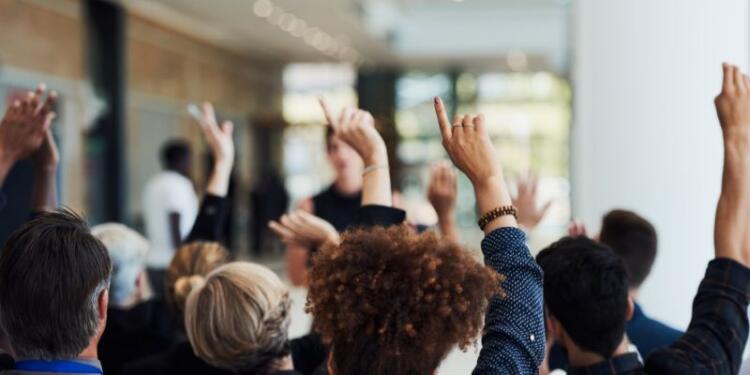 Gruppe von Personen, die sich melden, vor einem verschwommenen Hintergrund