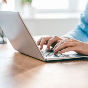 Ausschnitt eines Mitarbeiters: Nur seine Hände sind zu sehen, wie sie etwas in einen Laptop tippen